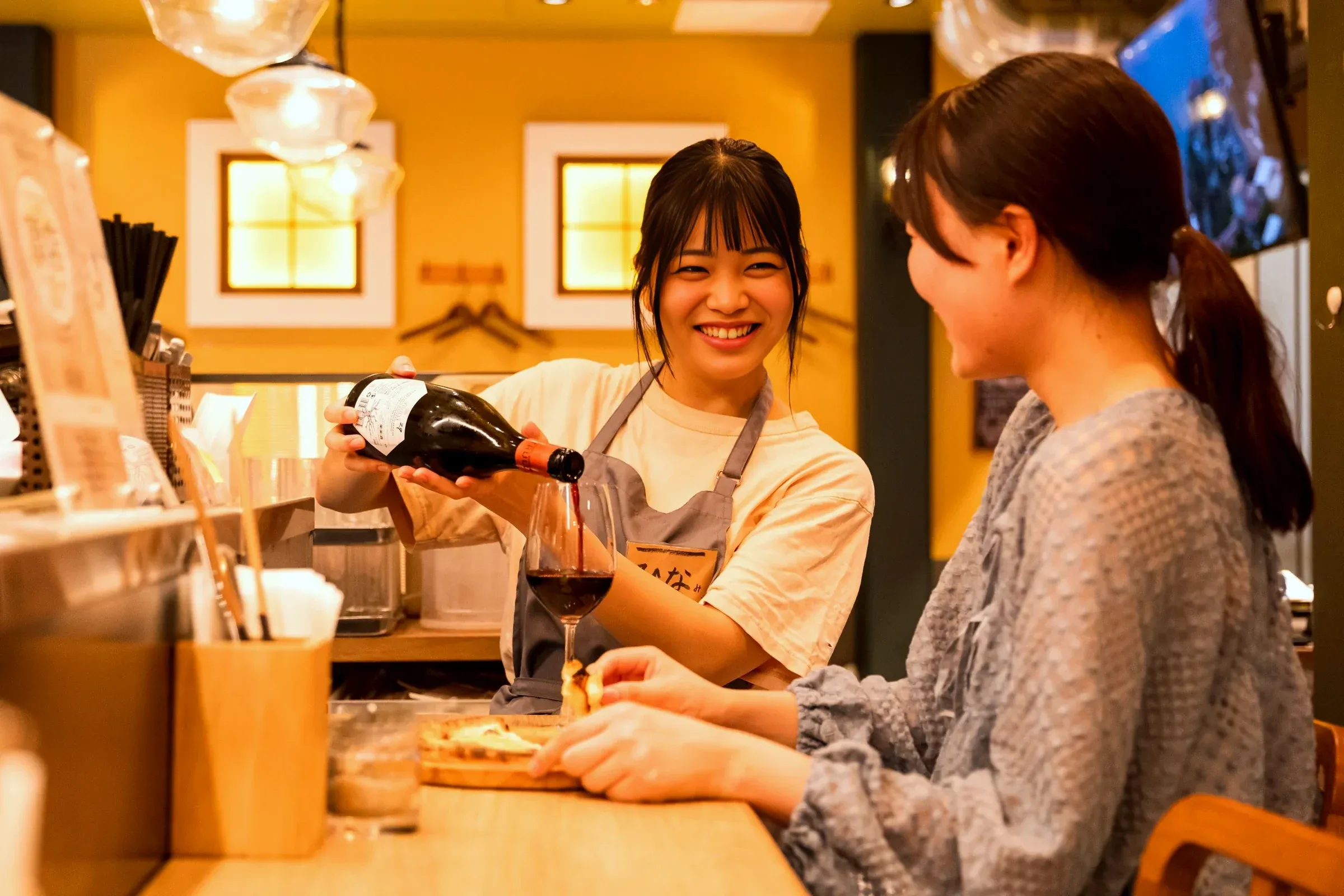 株式会社イタリアンイノベーションクッチーナの店内でワインを注ぐスタッフ